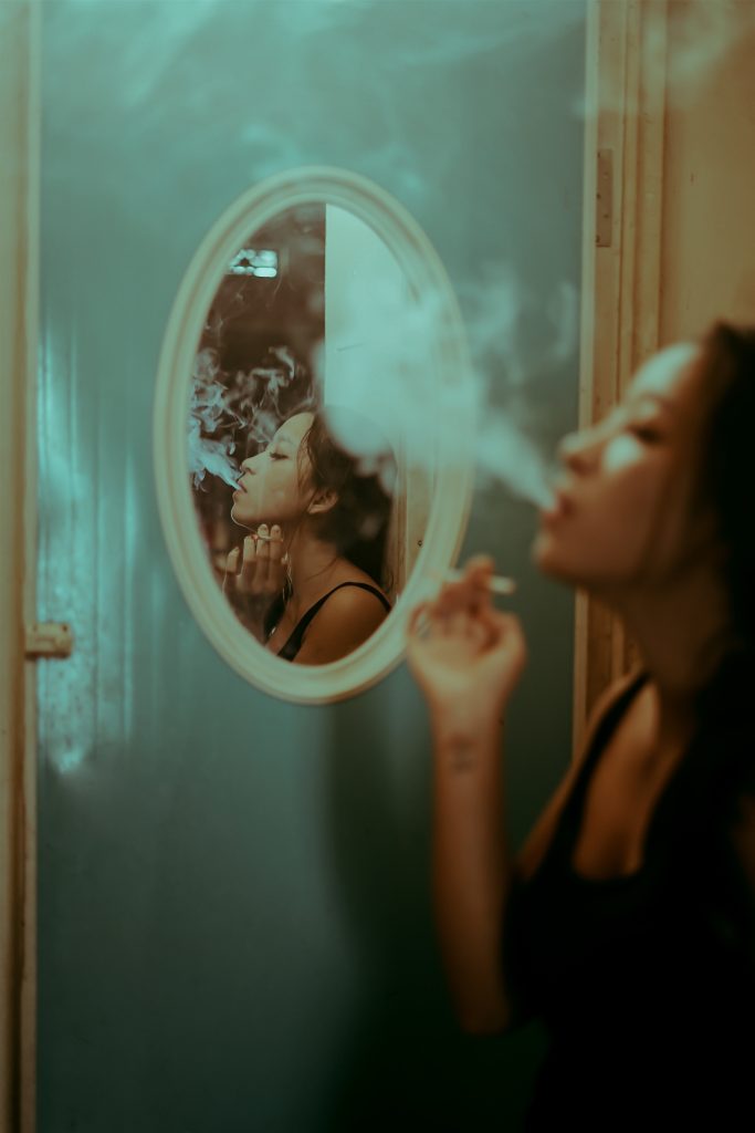 woman smoking in front of mirror