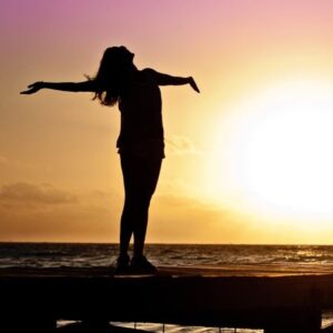 woman with arms out stretched at sunset